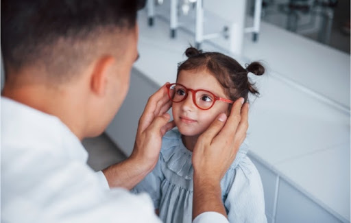 A young female patient being fitted for a pair of glasses by an optician at the eye care clinic