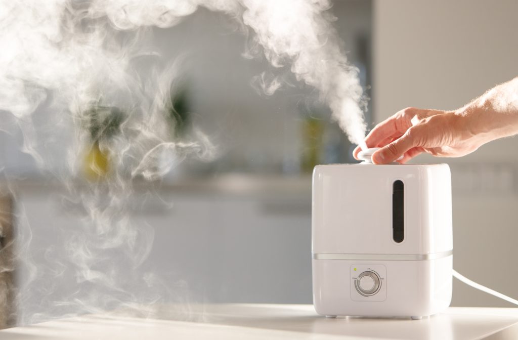 A person hand reaching to adjust a dial on a white humidifier in their home