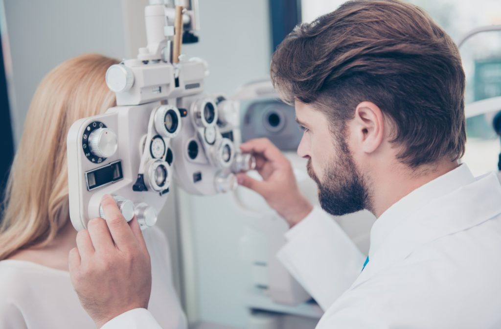 A male optometrist checking a female patient's eyes with a phoropter