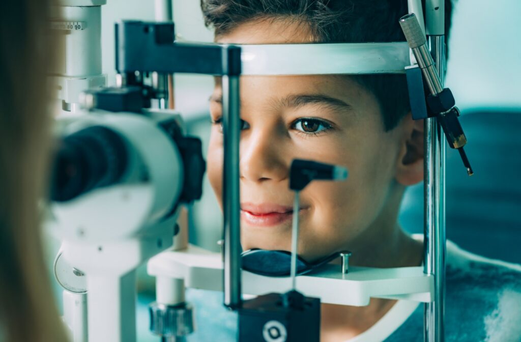 A young boy who experienced red eyes visiting the eye doctor for a comprehensive eye exam using a slit lamp.