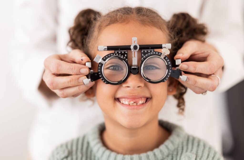 A young girl smiling while getting an eye exam.