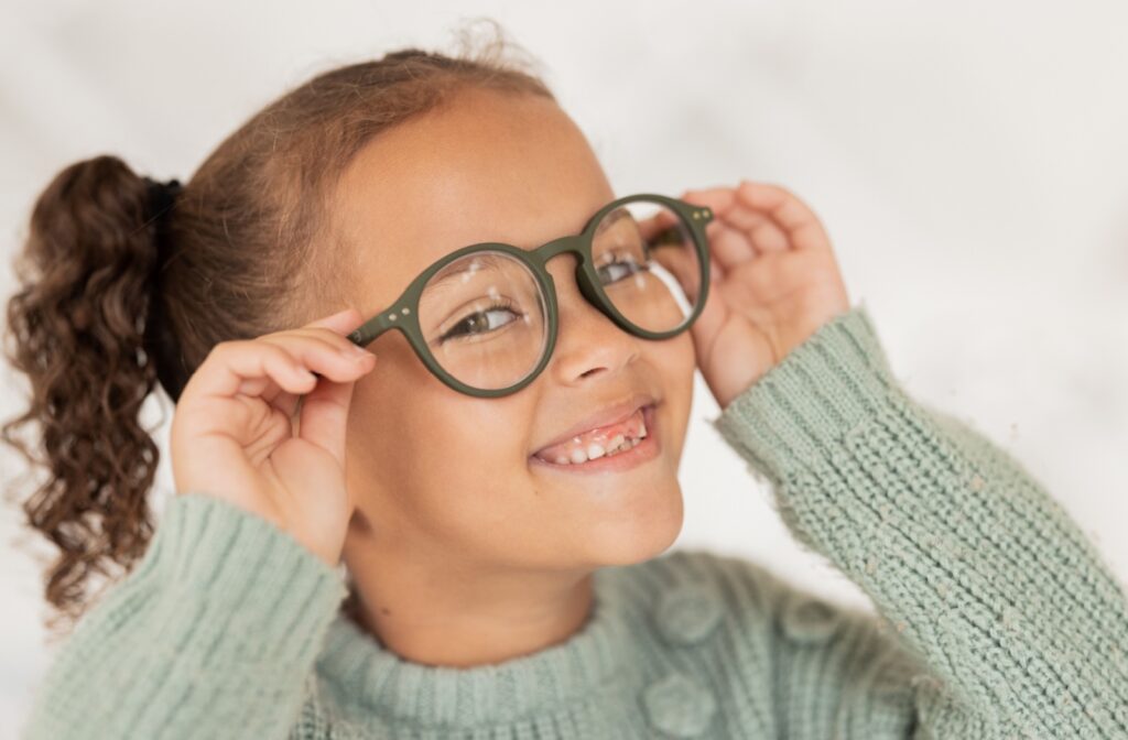 A young girl smiling while trying on her new pair of myopia control eyeglasses.