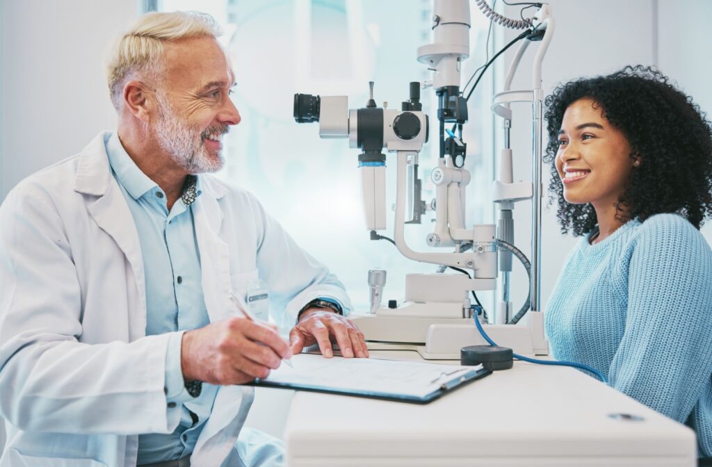 An optometrist smiling at his patient while discussing the results of her eye exam.