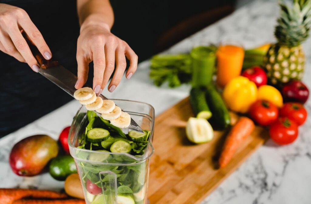 A person makes a smoothie next to a chopping board with a diverse selection of eye-healthy foods