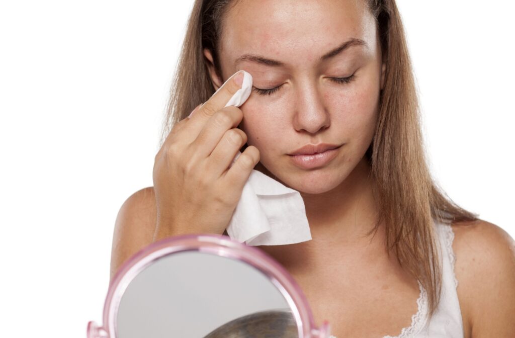 A woman using an eyelid wipe to promote better eyelid hygiene and avoid clogged meibomian glands and meibomian gland dysfunction.