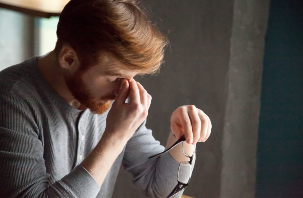 Man rubbing his eyes in discomfort, indicative of dry eyes or headache.