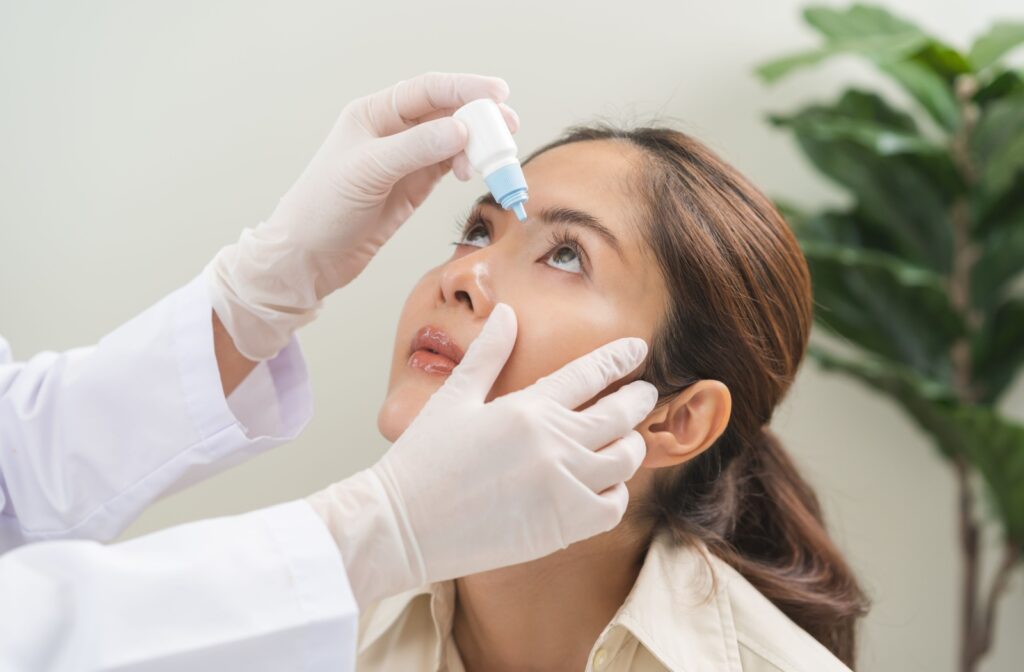 Doctor administering eye drops for a woman with dry eyes in a clinical setting.