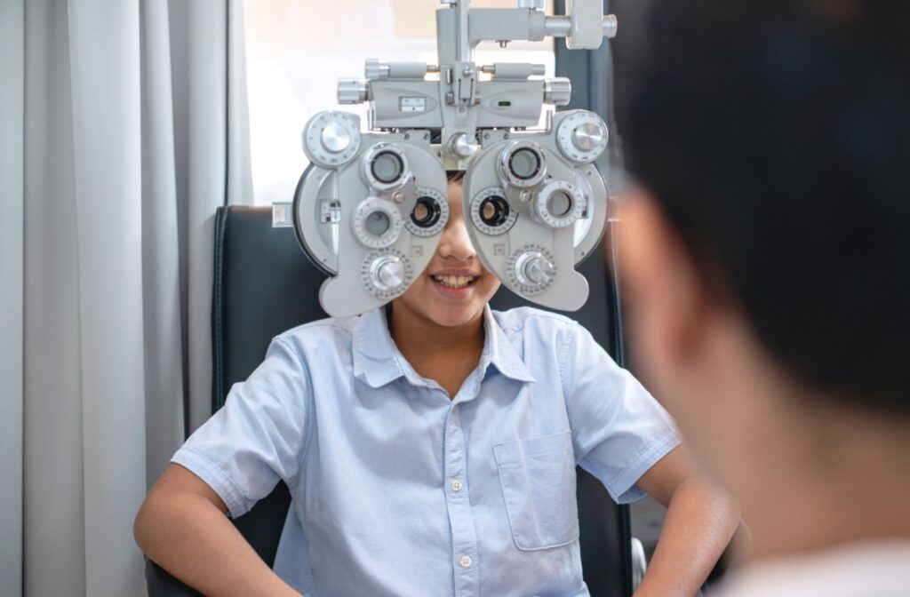 A child undergoing an eye exam, sitting in front of an optometry device to be fitted for glasses.