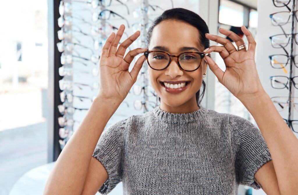 A person in an optometrist's clinic adjusts their new glasses.