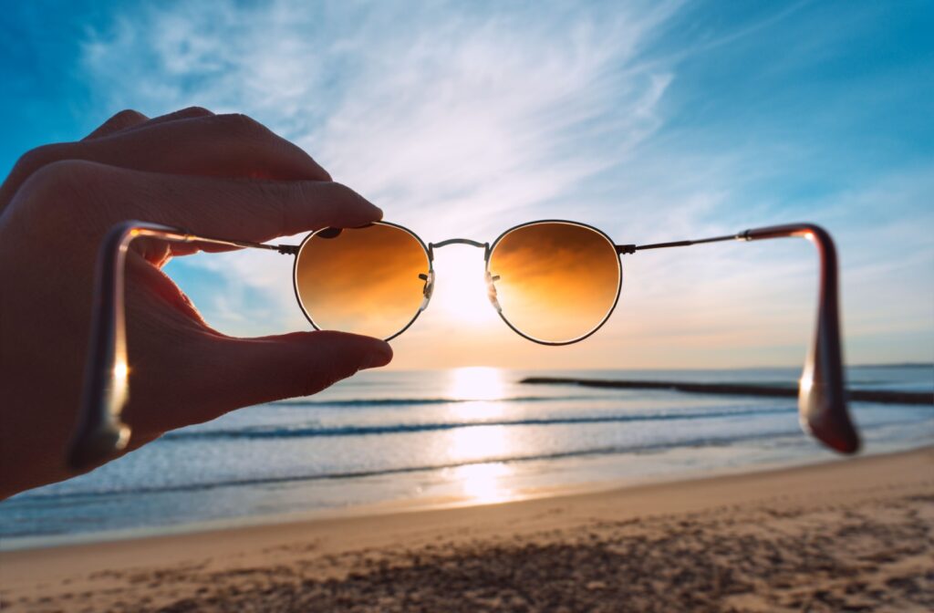 A hand holding a pair of sunglasses against the sun.
