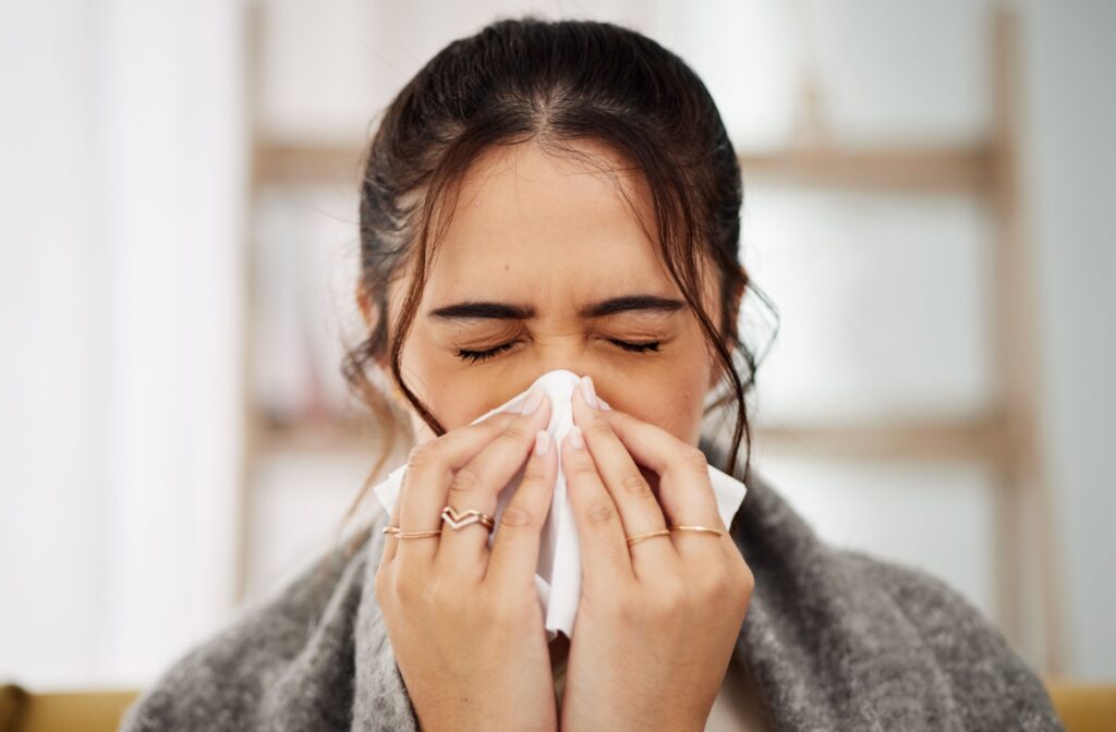 A person blowing their nose into a tissue.