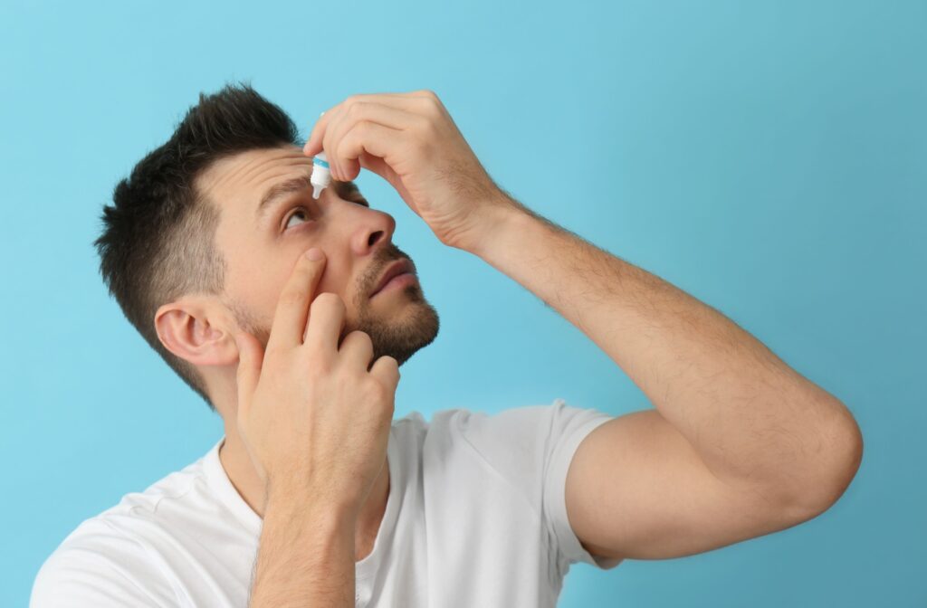 A person gently pulling their under-eye area to self-administer their eye drops.