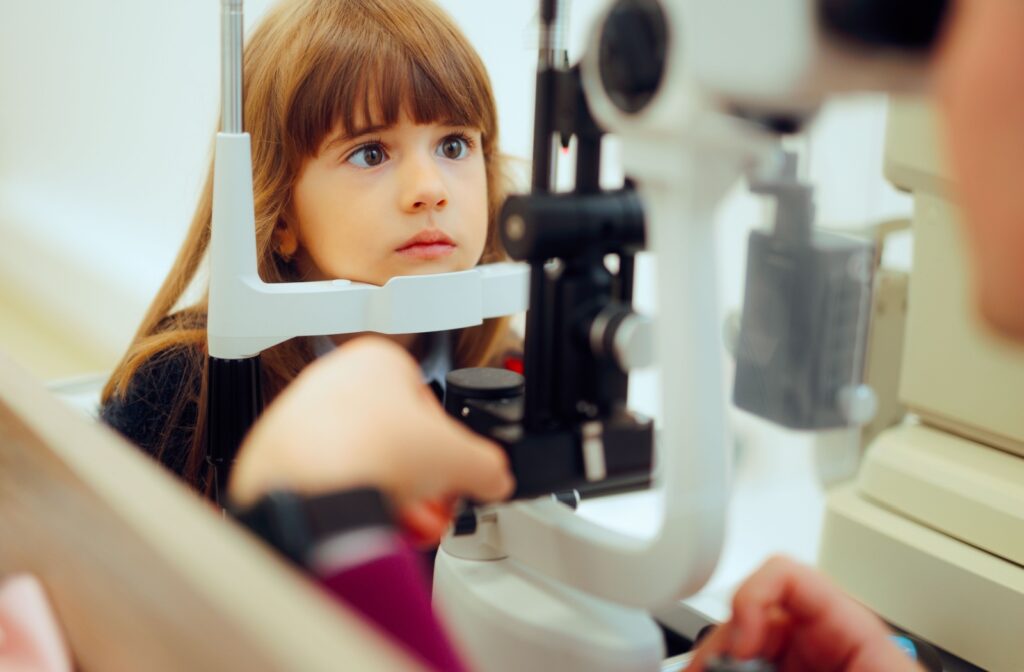 Child receiving an eye exam with a slit lamp at the optometrist’s office.