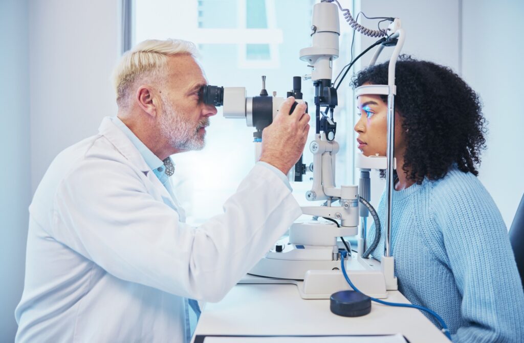 An optometrist examining a patient’s eyes using a slit lamp in a bright clinic setting.
