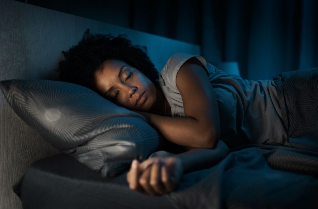 Woman laying down in bed with her eyes closed at night