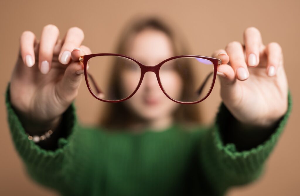 Close up of a person holding a pair of glasses and the background is blurry