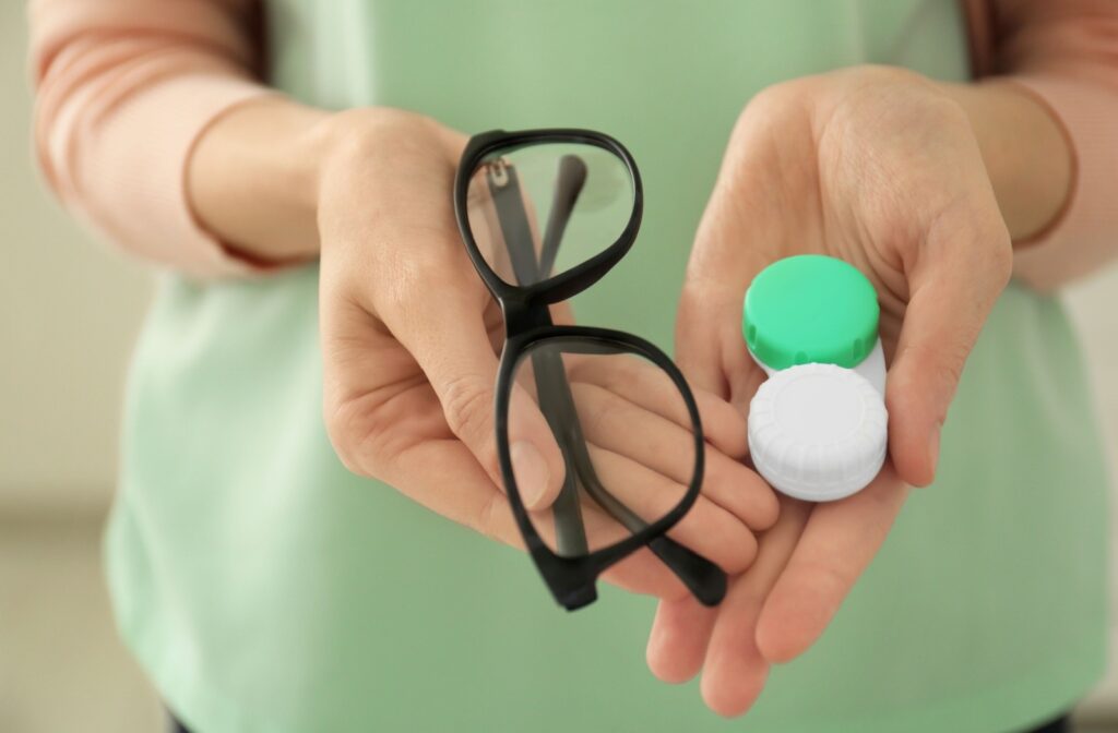 Hands holding both glasses and a contact lens case