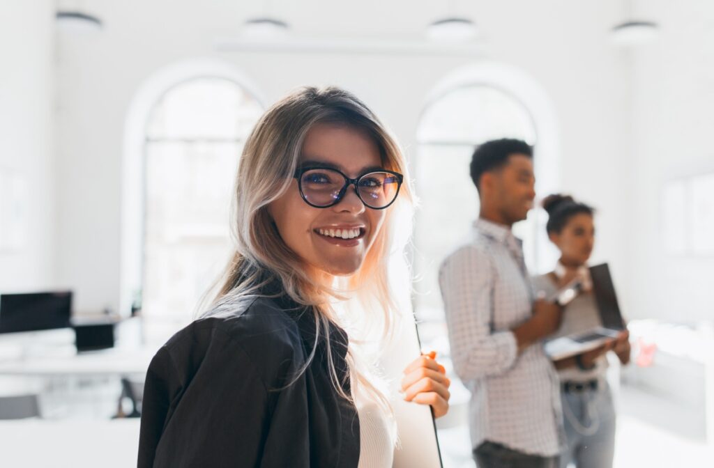 A person smiling while wearing a bold pair of glasses with a thick black frame