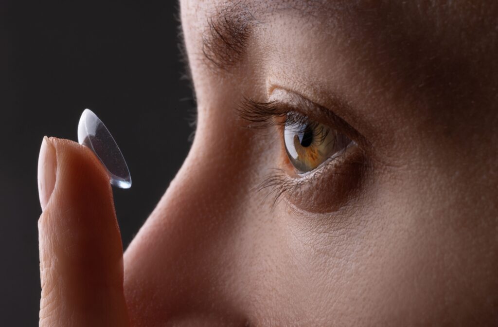 A close up of a person holding a contact lens that is about to be placed in their eye