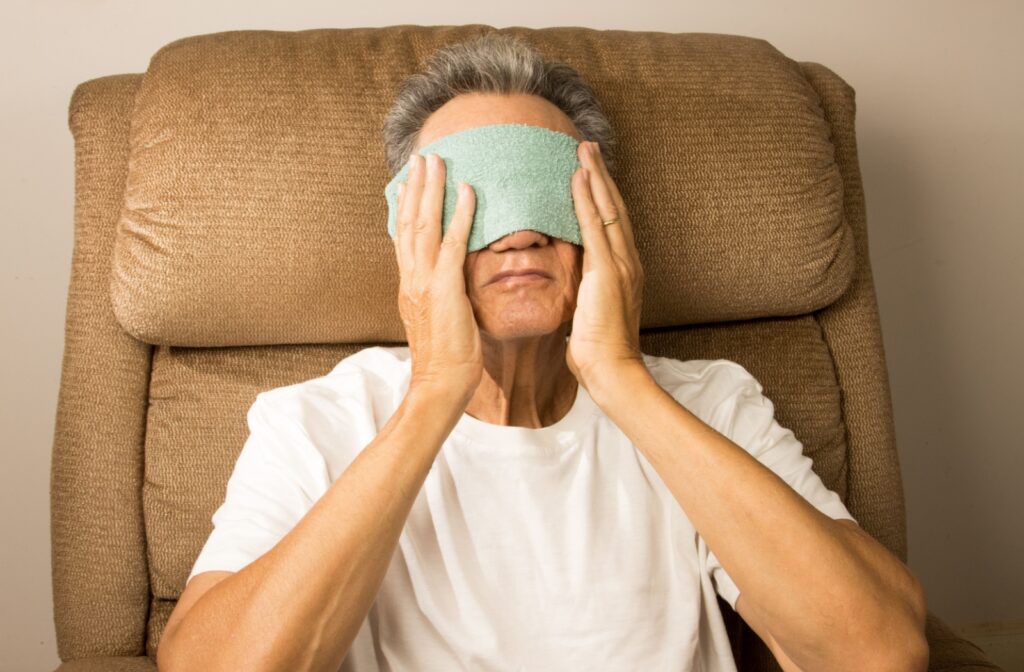 A person sitting in a chair with a warm eye mask placed over their eyes