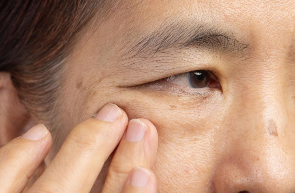 A person holding the side of their eye